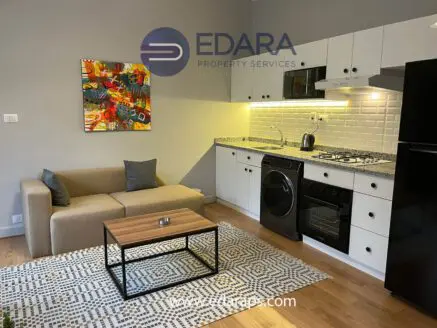Contemporary kitchen with a sofa, coffee table, and colorful artwork on the wall.