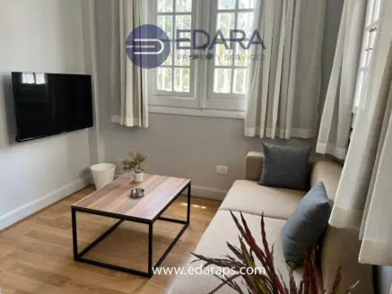 Living room featuring a beige sofa, wooden coffee table, and wall-mounted television.