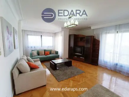 Spacious living room featuring a green sofa, a beige couch, and a wooden entertainment unit.