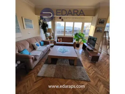 Spacious living room featuring a beige sofa, wooden coffee table, and a television unit with a plant.