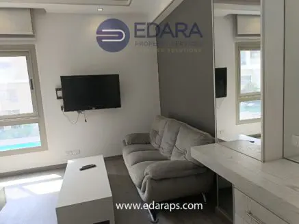 Living room featuring a gray sofa, wall-mounted television, and a mirrored cabinet.