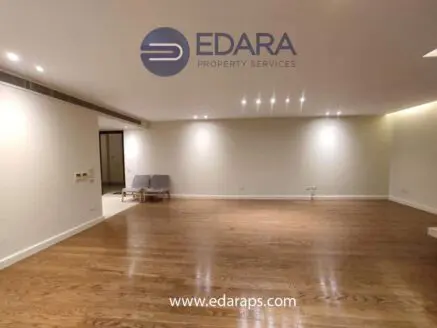 Spacious empty living room featuring wooden flooring and recessed lighting in a modern design.