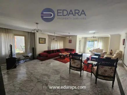 Spacious living room featuring a red sectional sofa, marble flooring, and large windows with natural light.