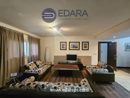 Living room featuring a sofa set with patterned upholstery and a television on a wooden table.