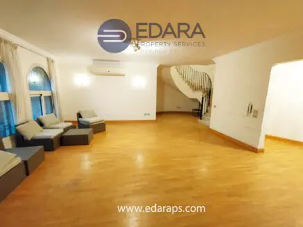 Interior view of a spacious living room featuring a seating area and wooden flooring.