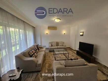 Modern living room featuring a beige sofa set and a flat-screen television on a wooden stand.