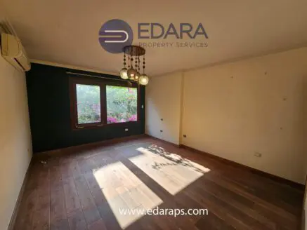 Empty interior room with wooden flooring and a large window allowing natural light to enter.