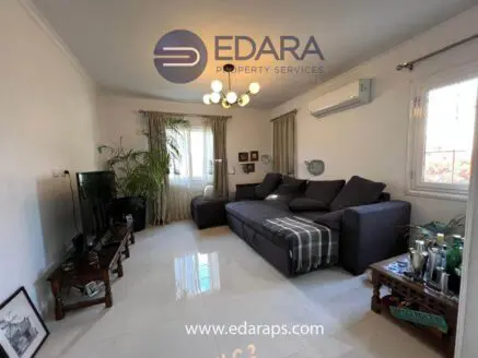 Contemporary living room featuring a dark gray sectional sofa and a television on a stand.