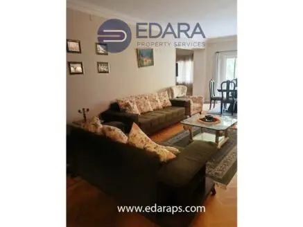 Living room featuring a green sofa set with floral cushions and a glass coffee table.