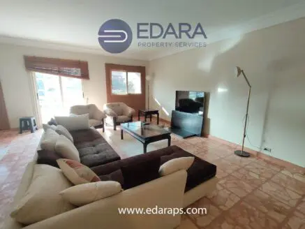 Spacious living room featuring a large sectional sofa, coffee table, and flat-screen television against a neutral wall.