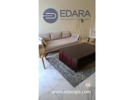 A modern sofa with a wooden frame and a rectangular coffee table on a rug in a living room setting.