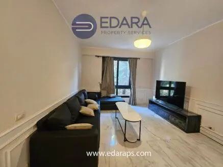 Modern living room featuring a black sofa, coffee table, and flat-screen television on a stand.