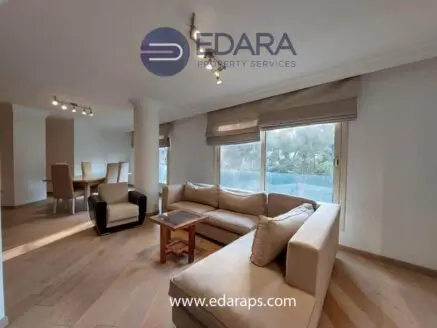 Contemporary living room featuring a beige sectional sofa and a dining table in a well-lit space.