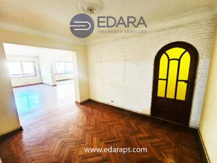 Interior view of a room featuring wooden flooring and a yellow door with glass panels.