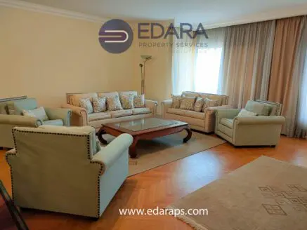 A living room featuring a light-colored sofa set with decorative cushions and a wooden coffee table.