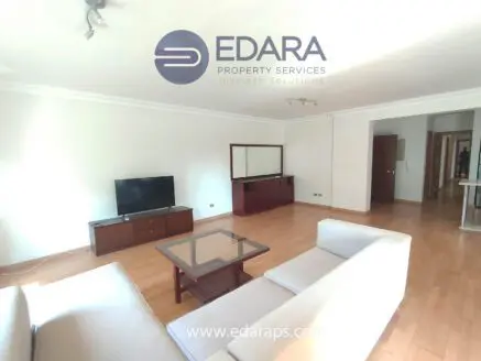 Living room featuring a light-colored sofa, coffee table, and television on a wooden stand.
