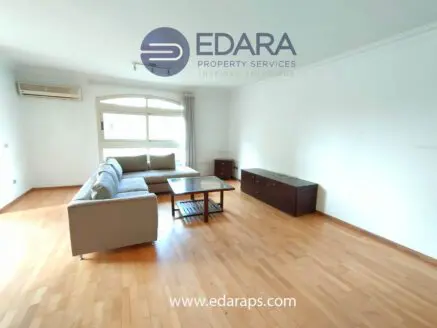 Bright living room featuring a light gray sofa, wooden coffee table, and storage cabinet against a white wall.