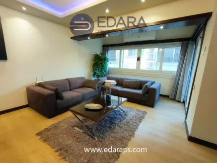 Contemporary living room featuring a gray sofa set and a glass coffee table with decorative items.