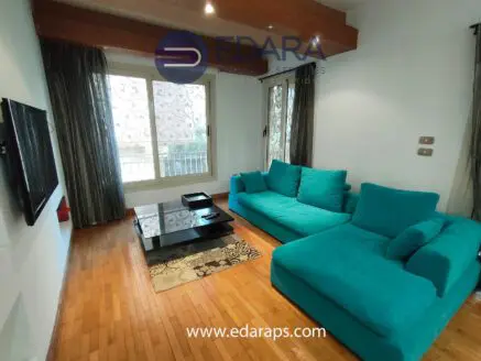 Living room featuring a turquoise sectional sofa and a black coffee table on a patterned rug.