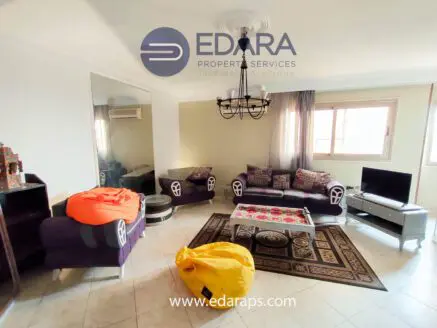 Living room featuring a purple sofa set, yellow bean bags, and a coffee table with decorative items.