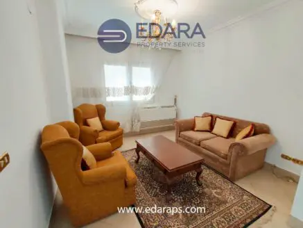 Living room featuring a beige sofa and two orange armchairs with decorative cushions.