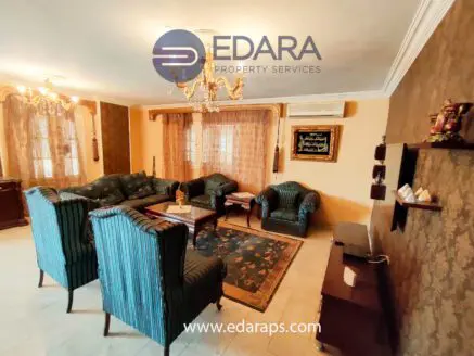 Living room featuring green upholstered chairs and a wooden coffee table with decorative items.