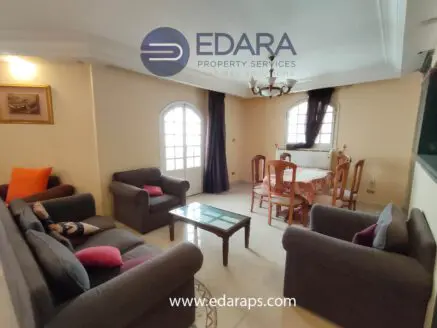 Interior view of a living room with gray sofas and a dining table in a well-lit space.