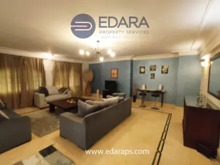 Spacious living room featuring two sofas, a coffee table, and a television against a blue wall.