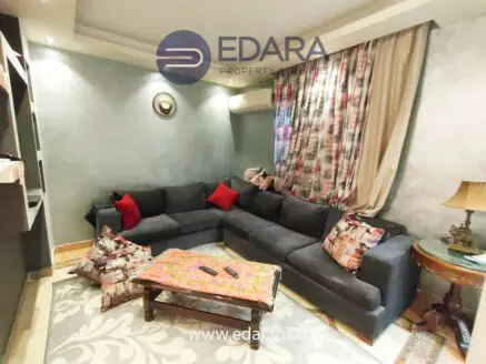 Cozy living room featuring a gray sectional sofa with red and patterned decorative pillows and a wooden coffee table.