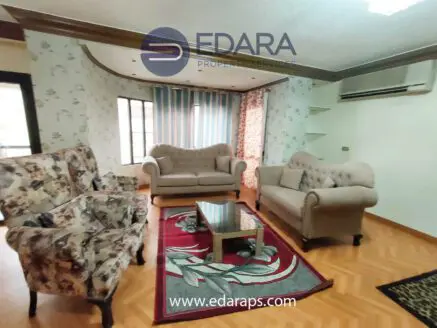 Living room featuring a floral sofa set, a beige couch, and a coffee table on a patterned rug.