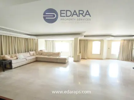 Bright living room featuring a large sectional sofa and natural light from windows with curtains.