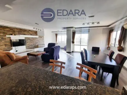 Spacious living room with a sofa, chairs, and a dining table in a contemporary design.