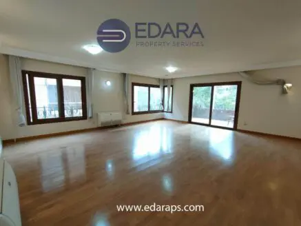 Bright living room featuring wooden flooring and large windows allowing natural light.