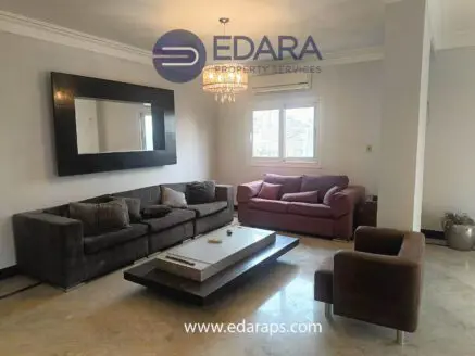 Contemporary living room featuring a dark sofa, coffee table, and armchair with a chandelier overhead.