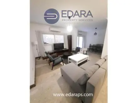 Contemporary living room featuring a gray sofa, coffee table, and television setup in a well-lit space.