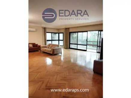 Bright living room featuring wooden herringbone flooring and large windows allowing natural light.