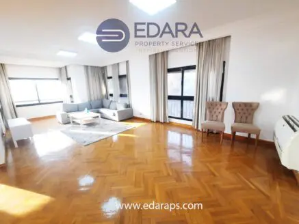 Bright living room featuring a gray sofa, two beige armchairs, and a coffee table on a wooden floor.