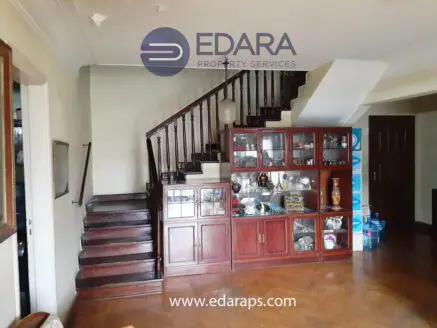 Interior view showing a wooden staircase and a cabinet with decorative items in a residential setting.