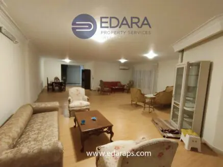 Spacious living room featuring a sofa set, coffee table, and armchairs in a neutral color scheme.
