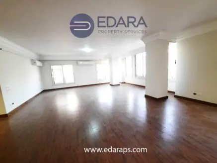 Large unfurnished room featuring wooden flooring and multiple windows for natural light.