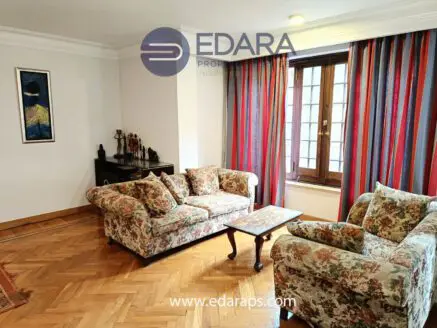 Living room featuring floral patterned sofas and a wooden coffee table in a well-lit space.