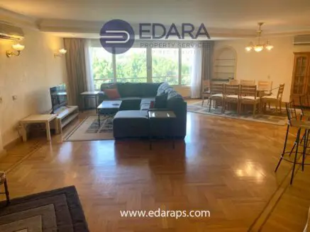 Spacious living room featuring a sectional sofa, dining table, and large windows for natural light.