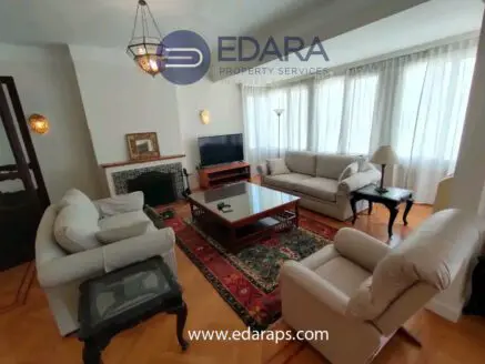 Living room featuring a light-colored sofa set, coffee table, and television in a well-lit space.