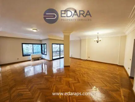 Bright living room featuring wooden flooring, large windows, and a chandelier in a residential space.