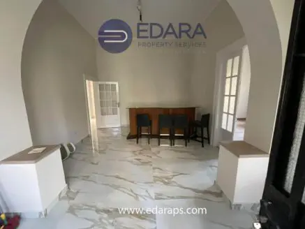 Interior view of a room featuring a bar counter with chairs and marble flooring.