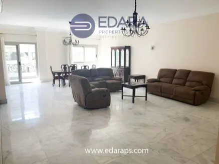 Spacious living room featuring brown reclining sofas and a wooden dining table with chairs.