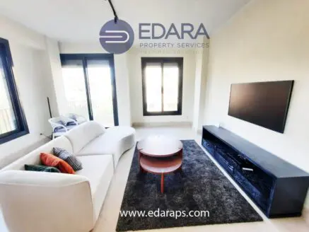 Contemporary living room featuring a white sofa, round coffee table, and a television unit against a neutral wall.