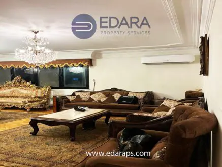 Luxurious living room featuring ornate furniture and a chandelier, with a large window and air conditioning unit.