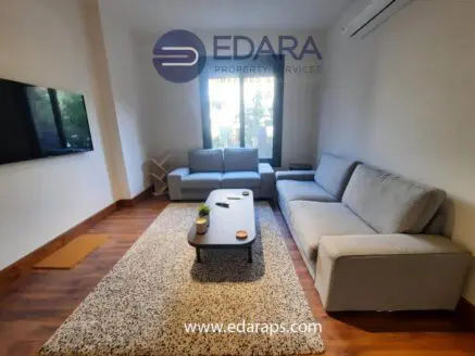 Living room featuring gray sofas, a coffee table, and a television mounted on the wall.