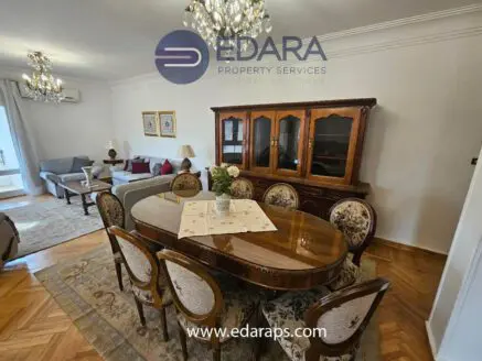 Dining room featuring a wooden table with ornate chairs and a decorative cabinet in a well-lit space.
